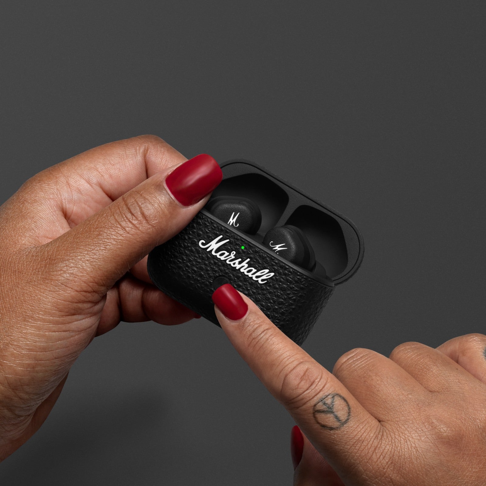 Hand holding Marshall Motif II A.N.C. earbud detail