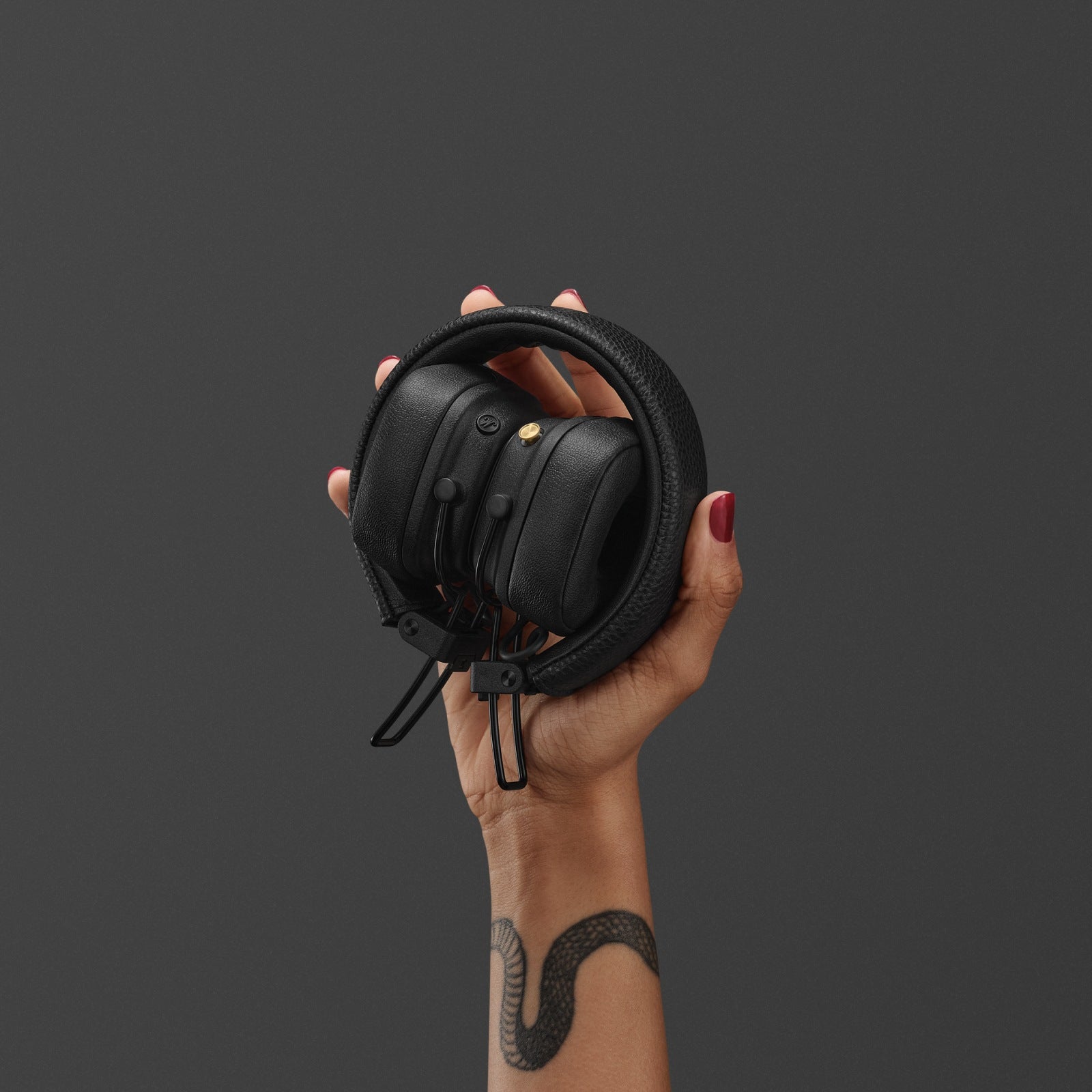 Hand holding folded Marshall Major V Black headphones