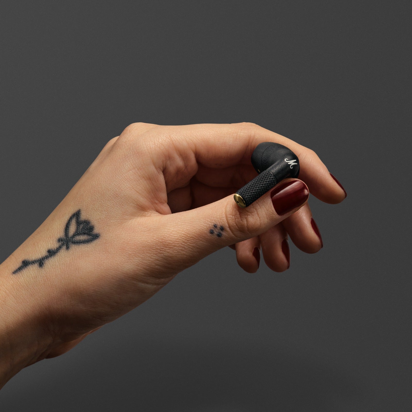 Hand holding Marshall Minor IV Black earbud charging case